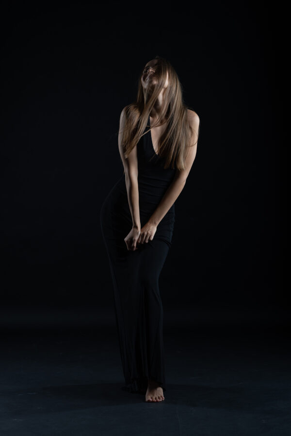 Künstlerisches Portrait der österreichischen Schauspielerin Laura Bilgeri im schwarzen Abendkleid vor dunklem Studiohintergrund.