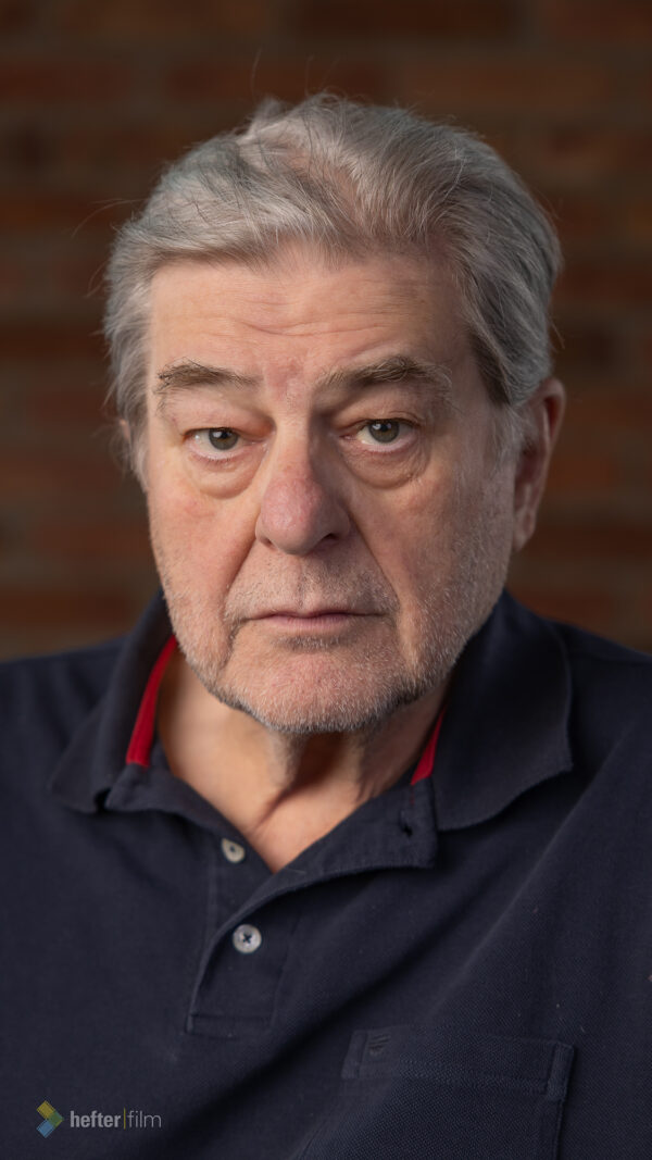 Porträt des österreichischen Schauspielers Erwin Steinhauer vor einer Backsteinwand.